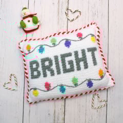 crochet christmas holiday themed pillow with Bright written and christmas lights