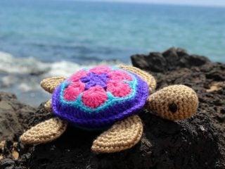 crochet sea turtle on a rock by the ocean