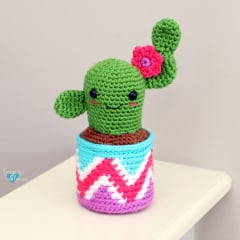 crochet smiling cactus amigurumi with a pink flower and colorful pot