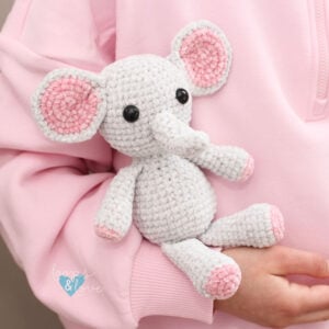 cuddly crochet grey and pink elephant in a child's arms