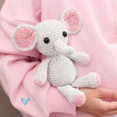 cuddly crochet grey and pink elephant in a child's arms