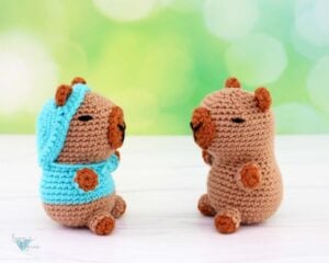 Crochet Capybara amigurumi facing each other. One with a sweater and one without.