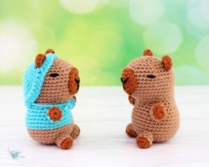 Crochet Capybara amigurumi facing each other. One with a sweater and one without.