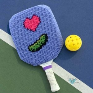 crochet pickleball paddle cover featuring a heart and pickle with a pickleball