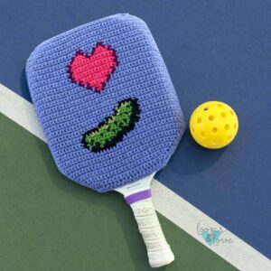 crochet pickleball paddle cover featuring a heart and pickle with a pickleball
